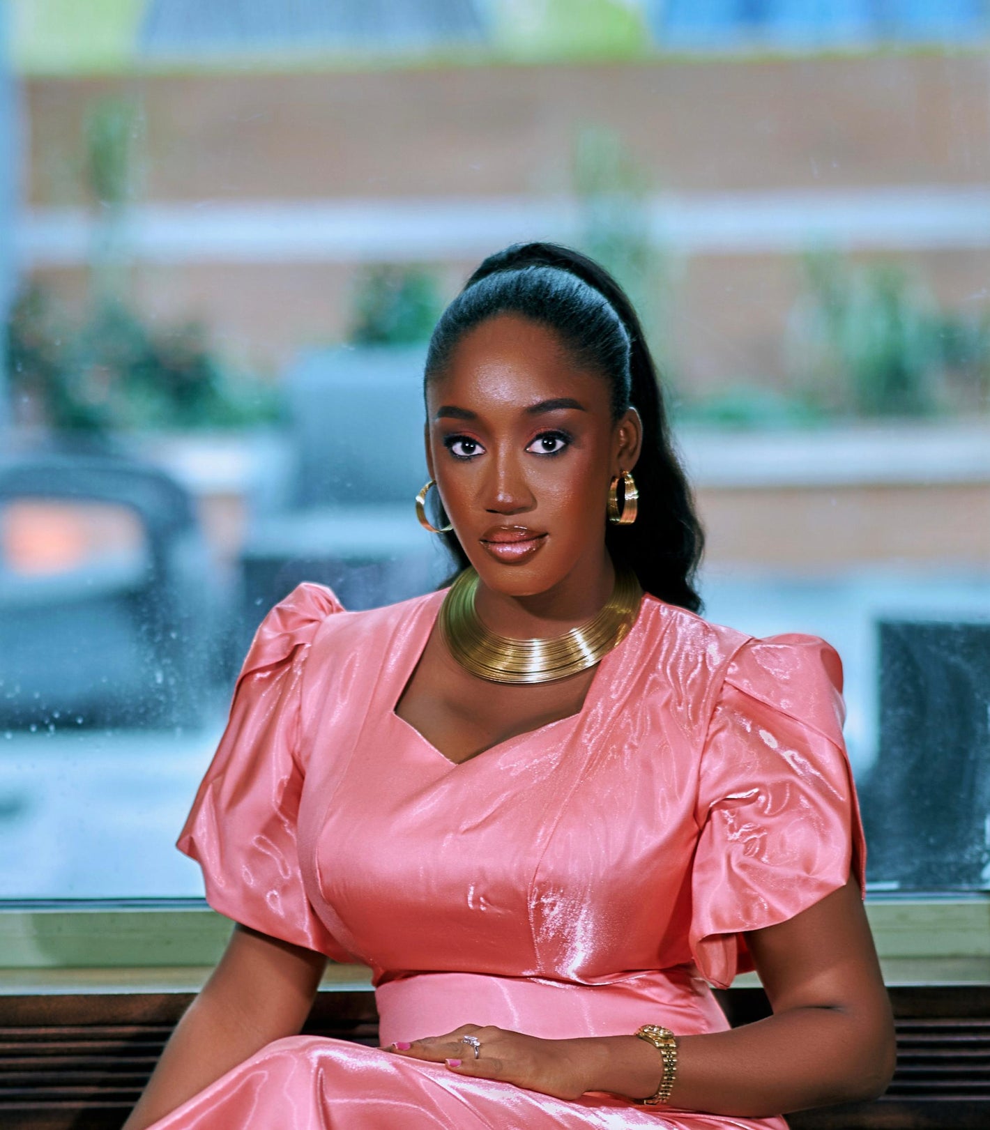 Woman in a pink dress sitting outdoors with blurred background